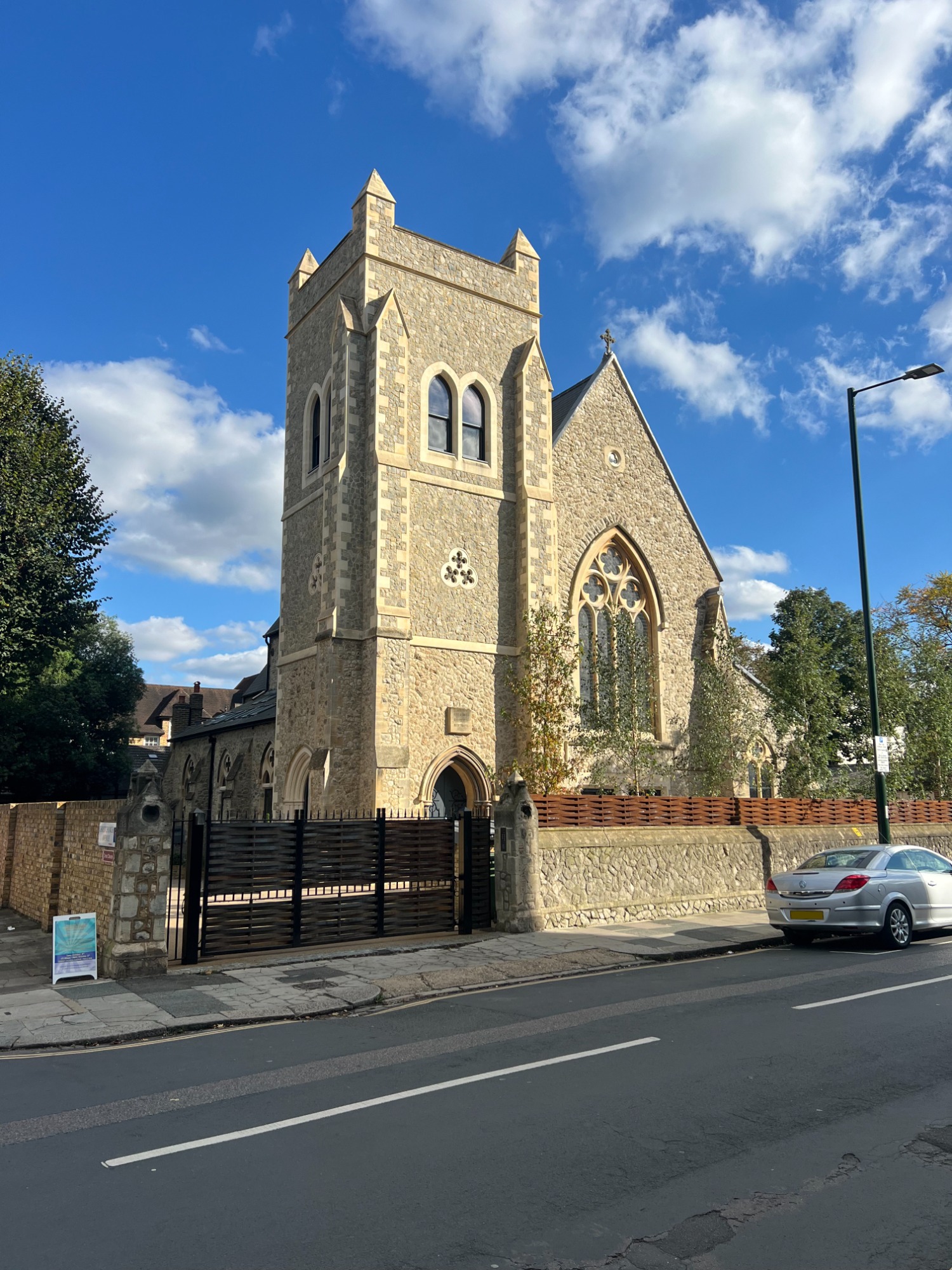 Christ Church, Teddington Stone building with tall tower and large windows, set against a blue sky.