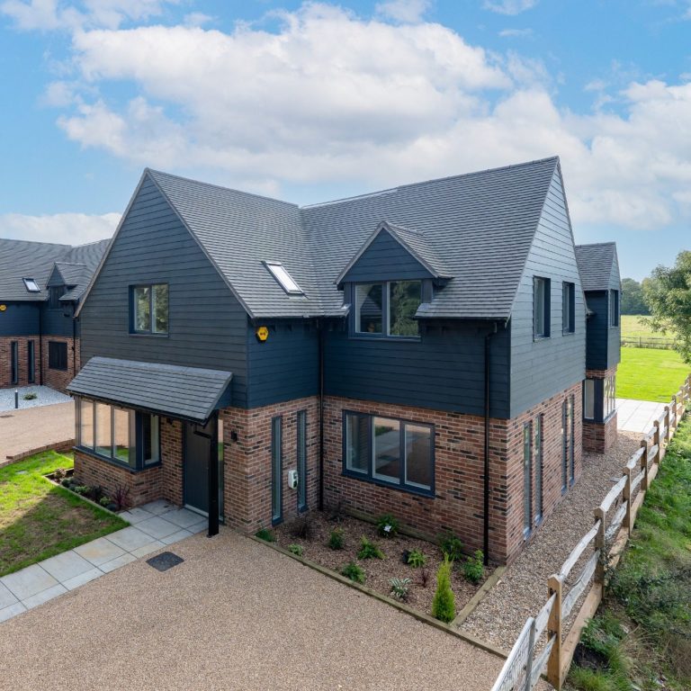 Modern new build houses in banstead countryside Modern two-storey house with a grey exterior and landscaped front garden.