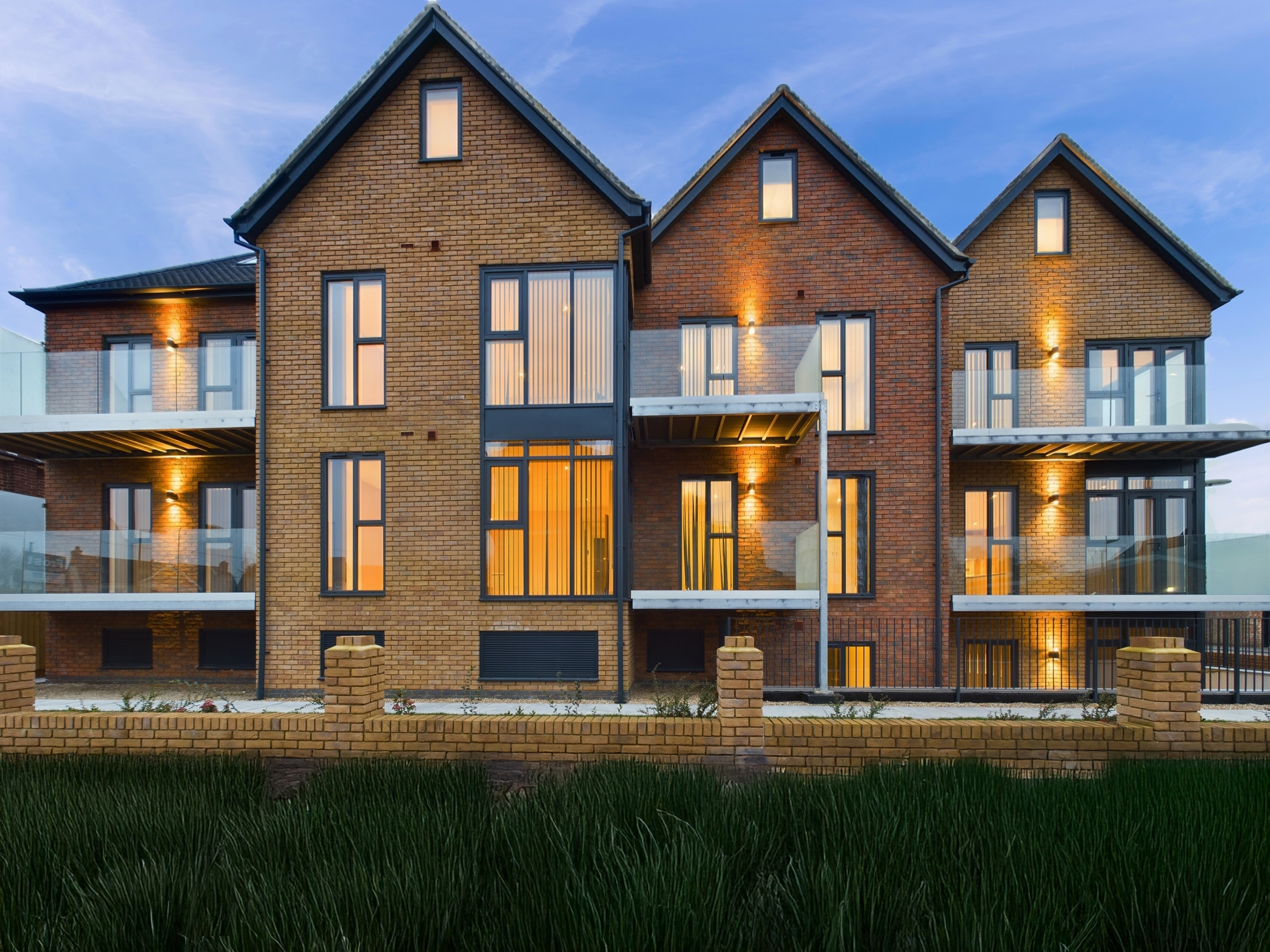 Headline House, Surrey Modern residential building featuring multiple balconies and large windows at dusk.
